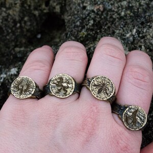 May include: Four silver rings with different designs. The rings feature a lion, a bird, a bee, and a wolf.