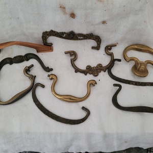 May include: Assortment of eight antique cabinet hardware pulls in various styles and finishes, including brass, copper, and black metal.