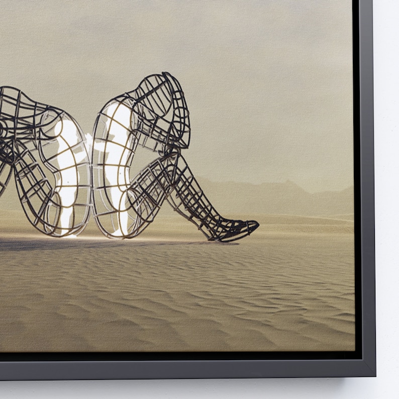 May include: A black metal sculpture of two figures sitting back to back in a desert landscape. The figures are made of a wire mesh and are partially filled with light.
