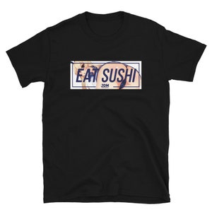 May include: Black t-shirt with a white rectangle graphic featuring a woman in a blue and white outfit and the text "EAT SUSHI JDM".