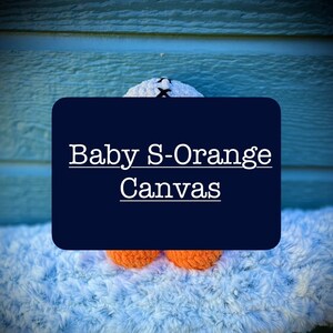 May include: A white canvas bag with the text "Baby S-Orange Canvas" on a blue background. The bag is sitting on a fluffy white surface.
