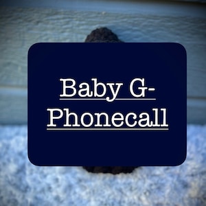 May include: A dark blue square sign with white text that reads "Baby G-Phonecall".