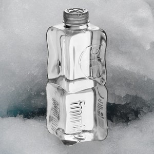 May include: A clear plastic bottle of water with a textured surface. The bottle is sitting on a bed of snow.