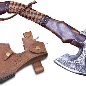 May include: A hand-forged Viking axe with a leather wrapped handle and a leather sheath. The axe head has a detailed design with intricate patterns.