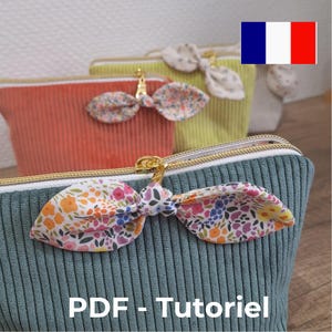 Peut inclure: Une collection de pochettes en velours côtelé bleu canard, corail et vert lime, chacune dotée d'une fermeture éclair dorée avec un nœud en tissu floral sur la tirette. Le texte PDF - Tutoriel est visible en bas de l'image.