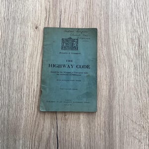 May include: A green booklet titled "The Highway Code" issued by the Ministry of Transport with the Authority of Parliament. The booklet includes supplementary notes and is published by His Majesty's Stationery Office.