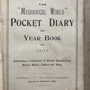 May include: A vintage book cover for "The Mechanical World Pocket Diary and Year Book for 1909." The beige cover features black text detailing the title, year, and publisher's details. It includes a collection of useful engineering notes, rules, tables, and data.