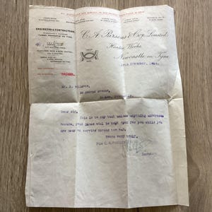 May include: A vintage letter from C.A. Parsons Coy Limited, Heaton Works, Newcastle on Tyne, with folded creases. The paper is cream-colored with blue and black text. The letter is on a wooden surface.