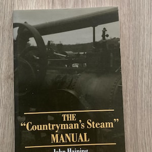 May include: A book titled "The Countryman's Steam Manual" by John Haining. The cover shows a black and white image of a steam engine. The title is in gold lettering, with a black background.