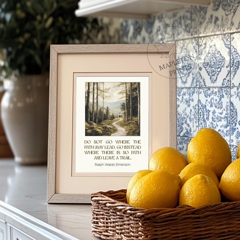 May include: A framed print with a quote by Ralph Waldo Emerson: "Do not go where the path may lead, go instead where there is no path and leave a trail." The print features a painting of a winding path through a forest.