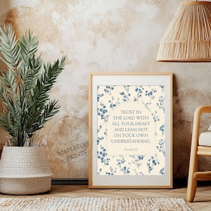 May include: A framed print with a beige background and blue floral accents. The text reads "Trust in the Lord with all your heart and lean not on your own understanding." The print is in a light wood frame.