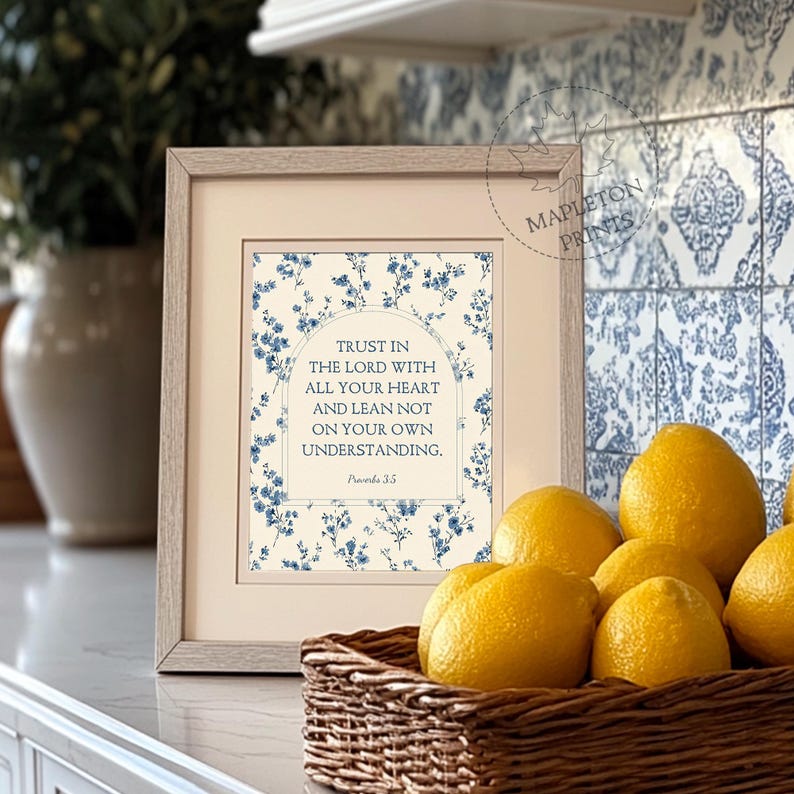 May include: A framed print with the text "TRUST IN THE LORD WITH ALL YOUR HEART AND LEAN NOT ON YOUR OWN UNDERSTANDING." The print has a floral design and is displayed with lemons in a woven basket.