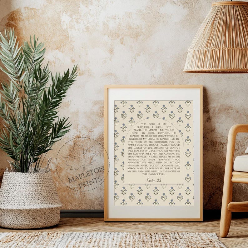 May include: A framed wall art print featuring the text of Psalm 23 centered within an arched design. The background displays a repeating pattern of small blue floral motifs on a cream-colored field. A circular watermark reads MAPLETON PRINTS.