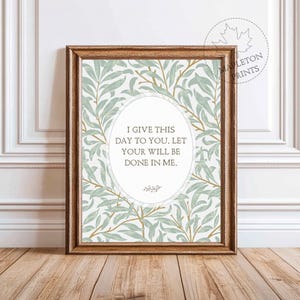 May include: Framed print with a light brown wooden frame. The print features a floral pattern in shades of green and gold on a white background. The text in the center reads: "I GIVE THIS DAY TO YOU. LET YOUR WILL BE DONE IN ME."