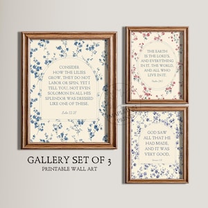 May include: A gallery set of three framed printable wall art pieces. Each piece features a floral pattern in blue or red, with inspirational quotes in a decorative font. The frames are a warm brown color.