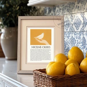 Puede incluir: Una impresi&oacute;n enmarcada con una paloma blanca sobre una mano sobre un fondo amarillo. La impresi&oacute;n incluye el texto "Nicene Creed" y el texto completo del credo.
