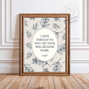 May include: A framed print with a beige background and a repeating pattern of dark blue leaves. The print features an oval with the text "I GIVE THIS DAY TO YOU. LET YOUR WILL BE DONE IN ME." The frame is a warm brown color.