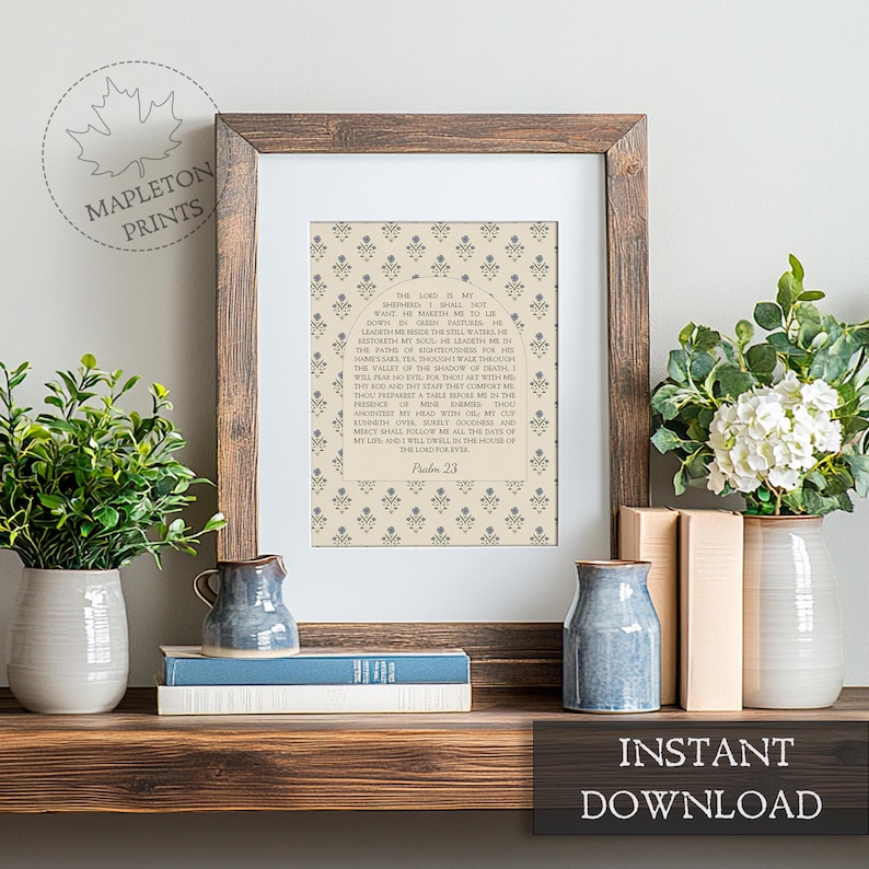 May include: A framed wall art print featuring the text of Psalm 23 centered within an arched design on a beige background with a repeating blue floral pattern. The print is housed in a dark brown wooden frame with a white mat border.