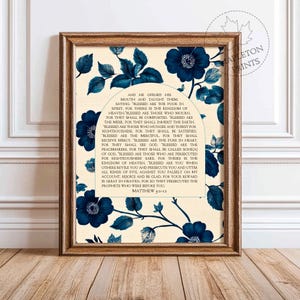 Puede incluir: Una impresión de arte de pared imprimible con un diseño floral azul y un fondo blanco. La impresión presenta un pasaje de la Biblia, Mateo 5:2-12, sobre las Bienaventuranzas. El texto está en fuente negra y está enmarcado por un arco floral azul.