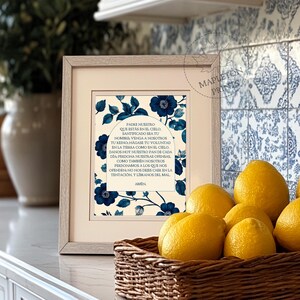 May include: A framed print with a blue and white floral design. The print features the Lord's Prayer in Spanish, "Padre Nuestro", with a blue floral archway surrounding the text.