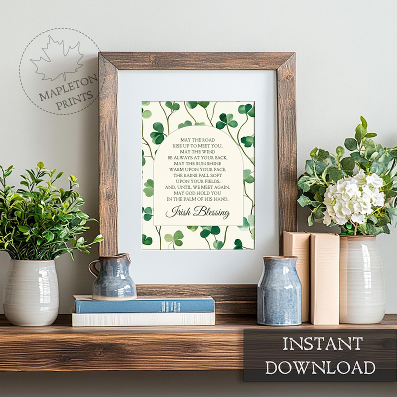 May include: Printable art print with a white background and green shamrock pattern. The print features a traditional Irish blessing with the text "May the road rise up to meet you. May the wind be always at your back. May the sun shine warm upon your face. The rains fall soft upon your fields. And, until we meet again, may God hold you in the palm of his hand. Irish Blessing."