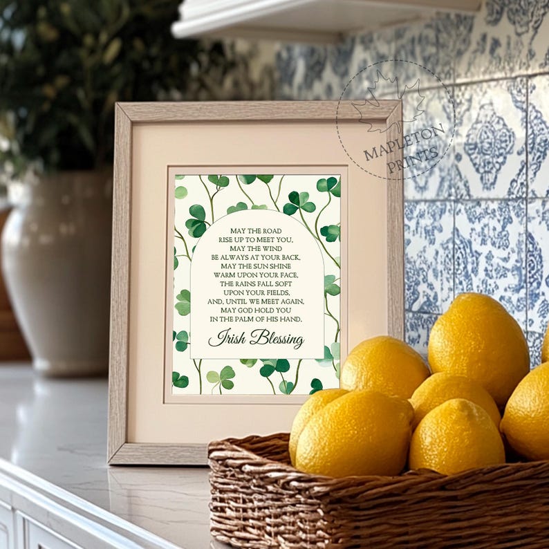 May include: A framed print with a white background and green shamrocks. The print features an Irish blessing that reads: "May the road rise up to meet you. May the wind be always at your back. May the sun shine warm upon your face. The rains fall soft upon your fields. And, until we meet again, may God hold you in the palm of his hand. Irish Blessing."