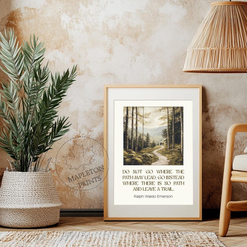 May include: A framed print with a quote by Ralph Waldo Emerson: "Do not go where the path may lead, go instead where there is no path and leave a trail." The print features a painting of a forest path with trees on either side.