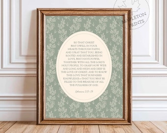May include: Framed print with a light green floral pattern background and a central oval containing text from Ephesians 3:17-19. The frame is a warm brown color. The print is from Mapleton Prints.
