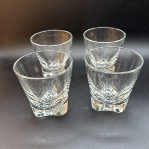 Puede incluir: Juego de cuatro vasos de chupito de vidrio transparente con un diseño facetado único. Los vasos tienen una base cuadrada y una boca ancha y redondeada.