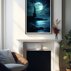 Op de afbeelding: Ingelijste kunstdruk met het Vrijheidsbeeld onder een grote, gloeiende maan. Het kunstwerk gebruikt een donker, sfeervol kleurenpalet met blauw- en tinten, wat een nachtelijke sc&egrave;ne oproept. De print wordt boven een witte open haard getoond.