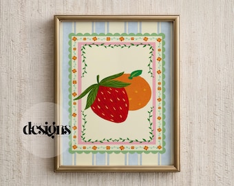 May include: A framed print featuring a vibrant illustration of a strawberry and an orange. The artwork is set against a cream background with a decorative border of pink, green, and orange floral elements. The frame is gold, and the print is labeled "designs".