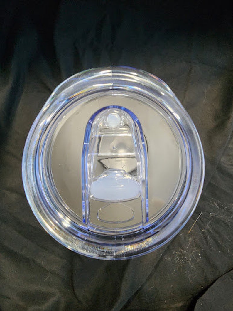 Op de afbeelding: Transparante plastic tumblerdeksel met een schuifsluiting. Het deksel heeft een helder, afgerond ontwerp met een lichtblauwe accentrand en een transparant schuifmechanisme. Het deksel is ontworpen om op een tumbler te passen.