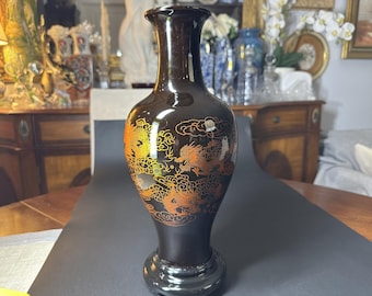 May include: A black ceramic vase with a gold dragon design. The vase has a narrow neck and a wide base.