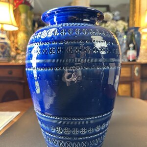 May include: A cobalt blue ceramic vase with a textured surface and decorative patterns. The vase features a wide body and a slightly flared rim. The patterns include geometric shapes and lines. The vase is a decorative home decor item.