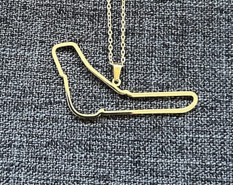 May include: A gold necklace with a pendant shaped like a race track.