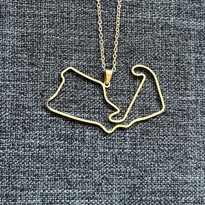 Peut inclure: Un collier en or avec un pendentif en forme de circuit de course.