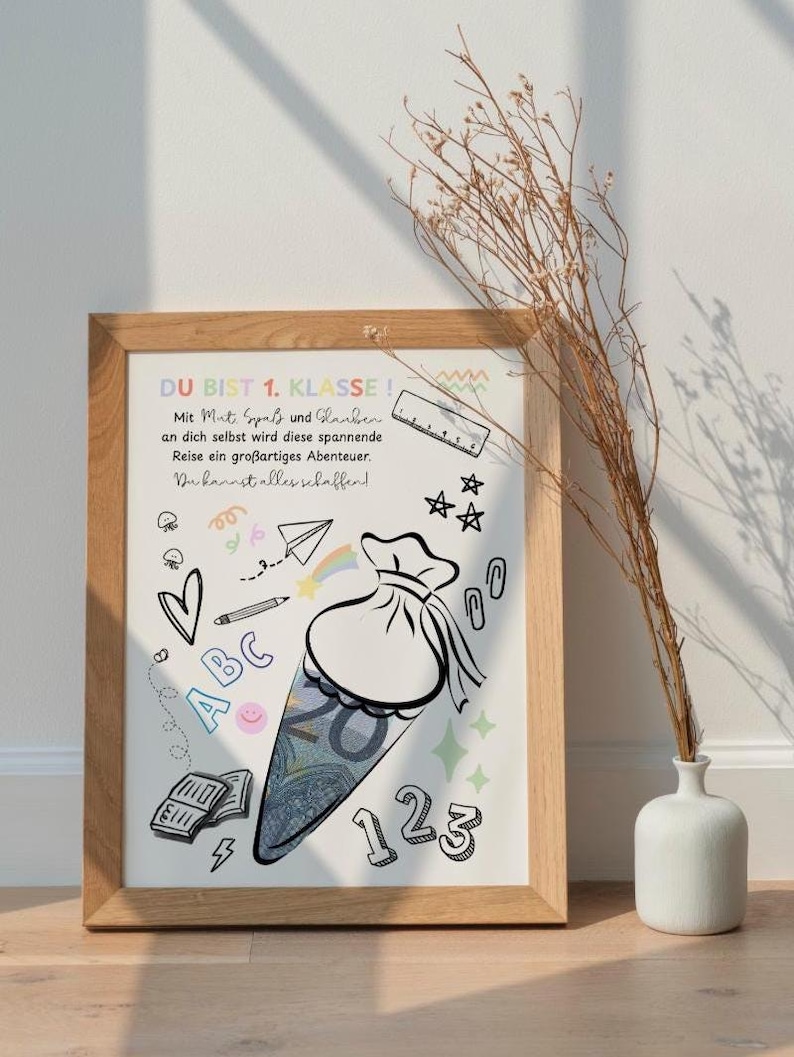 Puede incluir: Un estampado enmarcado con un marco de madera clara. El estampado presenta una ilustraci&oacute;n de dibujos animados de un cono escolar lleno de dinero, rodeado de garabatos como corazones, estrellas y n&uacute;meros. El texto en alem&aacute;n dice "DU BIST 1. KLASSE!" y otras frases.