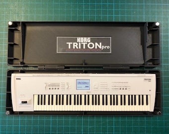 May include: A white Korg Triton Pro music workstation synthesizer with a black case. The keyboard has black and white keys, a small screen, and various buttons and knobs. The case is open, revealing the instrument.