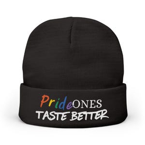 May include: Black beanie with the text "Pride Ones Taste Better" in rainbow and white lettering. The beanie is a knit cap, perfect for cold weather. The text is embroidered on the folded brim.