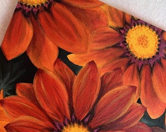May include: Close-up of a painting of three orange and yellow flowers with purple centers on a black background.
