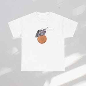 May include: White t-shirt featuring a graphic of a snail atop a pill with the number "401" and the word "Focus" in a speech bubble. The snail is gray and the pill is a light brown color.