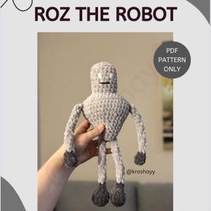 Puede incluir: Un juguete robot de crochet gris con ojos blancos y boca negra. El robot tiene brazos y piernas largos. El juguete está siendo sostenido por una mano. El texto "ROZ THE ROBOT" está en la parte superior de la imagen y "PDF PATTERN ONLY" está en un círculo en la parte superior derecha de la imagen. El texto "@kroshayy" está en la parte inferior de la imagen.