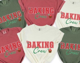 Peut inclure: Cinq t-shirts de couleurs différentes avec le texte "Baking Crew" et un graphique de cupcake rouge et blanc. Les chemises sont en rouge, vert, blanc et deux nuances de vert.
