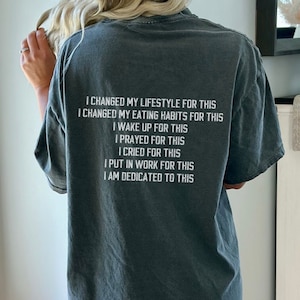 May include: A dark gray t-shirt with white text that reads "I changed my lifestyle for this I changed my eating habits for this I wake up for this I prayed for this I cried for this I put in work for this I am dedicated to this"