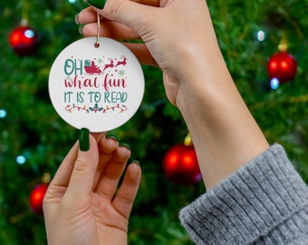 May include: White ceramic Christmas ornament with the text "Oh what fun it is to read" in green and red lettering. A red sleigh with a Santa figure is depicted above the text.