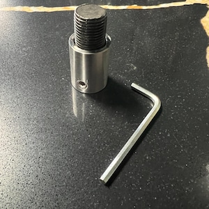 May include: A silver metal connector with a black threaded end and a hex wrench.