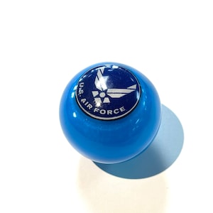 May include: A blue round gear shift knob with a white U.S. Air Force logo.
