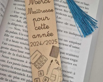 May include: A wooden bookmark with a blue tassel. The bookmark has a laser-engraved design of school supplies, including a pencil, scissors, an apple, a paint palette, a paintbrush, a backpack, and alphabet blocks. The text "Merci Maîtresse pour cette année 2024/2025" is engraved on the bookmark.