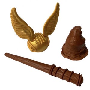 Könnte beinhalten: Ein goldener Schnatz mit detailliertem Flügeldesign, ein brauner Zauberstab mit Spiraldetails und ein brauner Sprechender Hut. Diese Artikel stammen aus der Zaubererwelt.