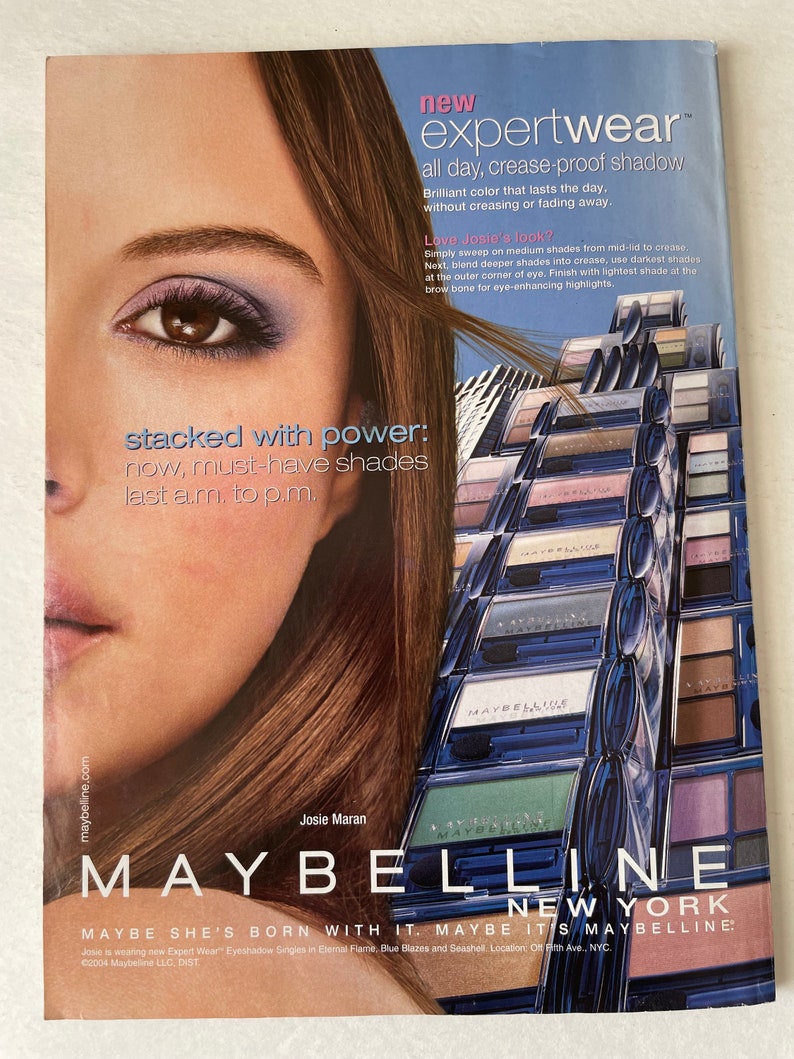 May include: A close-up of a woman's eye with eyeshadow applied. The image features a variety of eyeshadow palettes in blue, green, and purple shades. The text "new expert wear all day, crease-proof shadow" is featured at the top of the image. The text "MAYBELLINE NEW YORK MAYBE SHE'S BORN WITH IT. MAYBE IT'S MAYBELLINE." is featured at the bottom of the image.